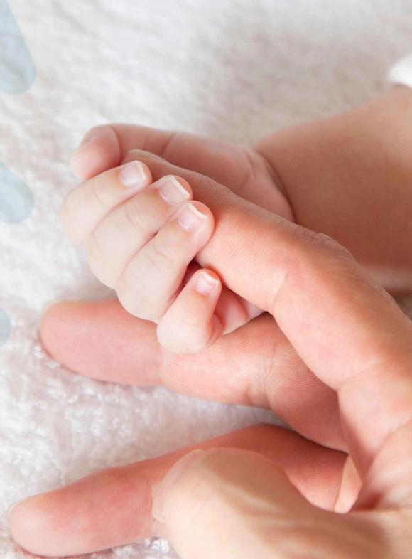 Mano de un bebé agarrando el dedo de un adulto, representando la maternidad tras un tratamiento exitoso de fertilidad en FIV Valencia